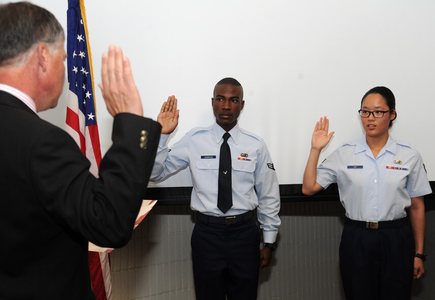 Airman 1st Class Adeola Adebojeyo and Airman 1st Class Rebekah Lee take the Oath of Allegiance with Kenneth Bawden Jr., the supervisory immigration services officer, at Fairchild Air Force Base, Washington, Aug. 4 2014. Adebojevo, a 92nd Force Support Squadron career development apprentice, is a native from Nigeria and moved to the U.S. almost two years ago to join the rest of his family. Lee, a 92nd FSS force management apprentice, has been in the U.S. since 2007 and is a native from South Korea. (U.S. Air Force photo by Senior Airman Ryan Zeski/Released)