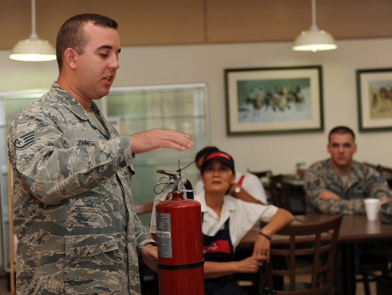 U.S. Air Force Staff Sgt. Christopher Johnston, 7th Civil Engineer Squadron fire prevention inspector, explains the use and importance of a fire extinguisher July 30, 2014, at Dyess Air Force Base, Texas. The purpose of teaching employees how to use the fire extinguisher is to prepare them to respond in the event of an actual fire. Across the Air Force, 90 percent of all fires are extinguished before the fire department arrives. (U.S. Air Force photo by Airman 1st Class Autumn Velez/Released)