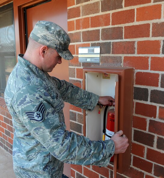 U.S. Air Force Staff Sgt. Shayne Anglin, 7th Civil Engineer Squadron fire prevention inspector, checks the expiration date on a fire extinguisher July 15, 2014, at Dyess Air Force Base, Texas. As part of fire prevention, Anglin is responsible for inspecting buildings across the base to ensure each building meets fire safety codes. (U.S. Air Force photo by Airman 1st Class Autumn Velez/Released)