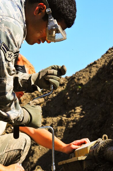 Airman 1st Class Eric Mata, 91st Missile Maintenance Squadron hardened intersite cable system technician, loosens the bolts on a splice case outside of a missile alert facility in North Dakota, July 31, 2014. Their primary mission is to maintain the HICS network, comprised of 1,535 linear miles of cable and 47 cable air dryers, spanning across 8,500 square miles of land.  (U.S. Air Force photo/Senior Airman Brittany Y. Bateman)  