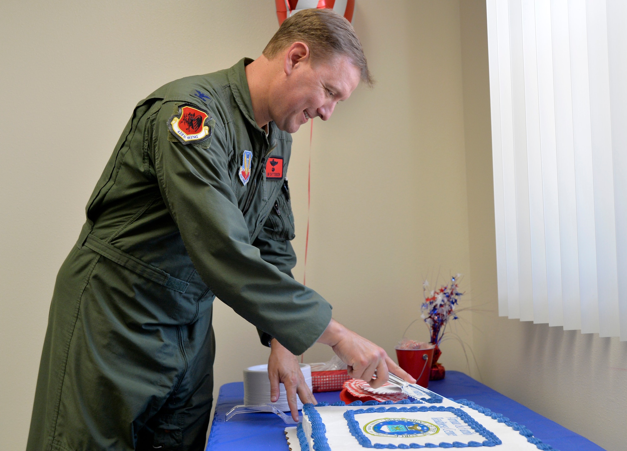 Col. James Chittenden, 432nd Wing/432nd Air Expeditionary Wing Vice Commander, cuts a cake to start the Creech Airman & Family Readiness Center grand opening event July 31, 2014, at Creech Air Force Base, Nev. The new location includes a larger classroom, private offices and free Wi-Fi to allow the A&FRC staff to provide enhanced services to Creech Airmen and their families. (U.S. Air Force photo by Tech. Sgt. Shad Eidson/Released)