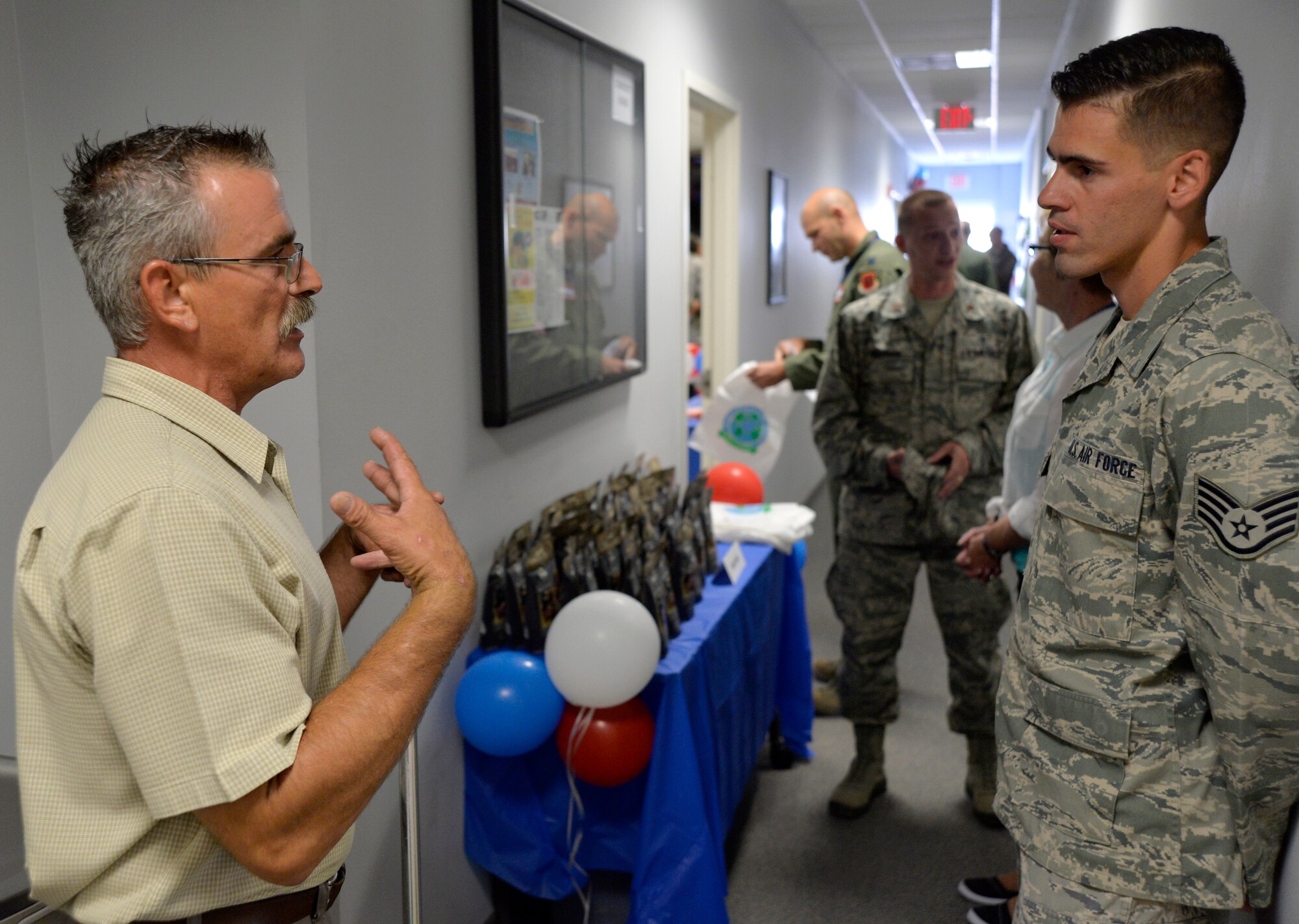 Mike Fedak, Creech Airman & Family Readiness Center director, left, talks about A&FRC services with a visitor during the grand opening event July 31, 2014, at Creech Air Force Base, Nev. The A&FRC provides Airmen and families with activities and services which promote self-sufficiency, mission readiness and adaptation to the Air Force way of life. (U.S. Air Force photo by Tech. Sgt. Shad Eidson/Released)
