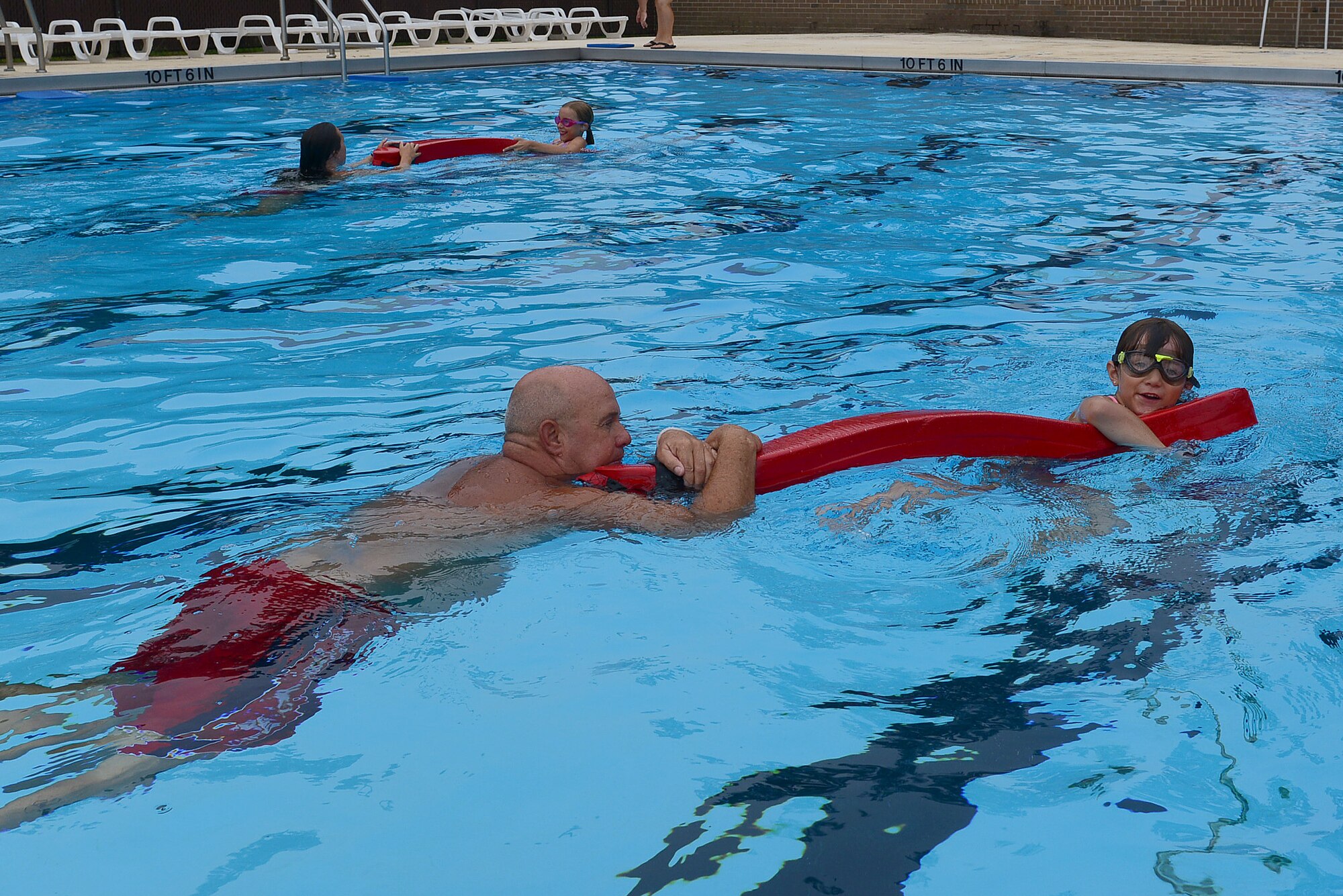 Jaidan and Megan Woods, daughters of Senior Master Sgt. James Woods, 9th Air Force Logistics superintendent, bring A Woodland Pool lifeguard, and Tim Godwin, 20th Force Support Squadron outdoor recreation director, to safety during a simulated rescue at Woodland Pool, Shaw Air Force Base, S.C., Aug. 1, 2014. Each child not only learns how to swim, but the safety procedures when in certain predicaments. (U.S. Air Force photo by Airman 1st Class Diana M. Cossaboom/Released)
