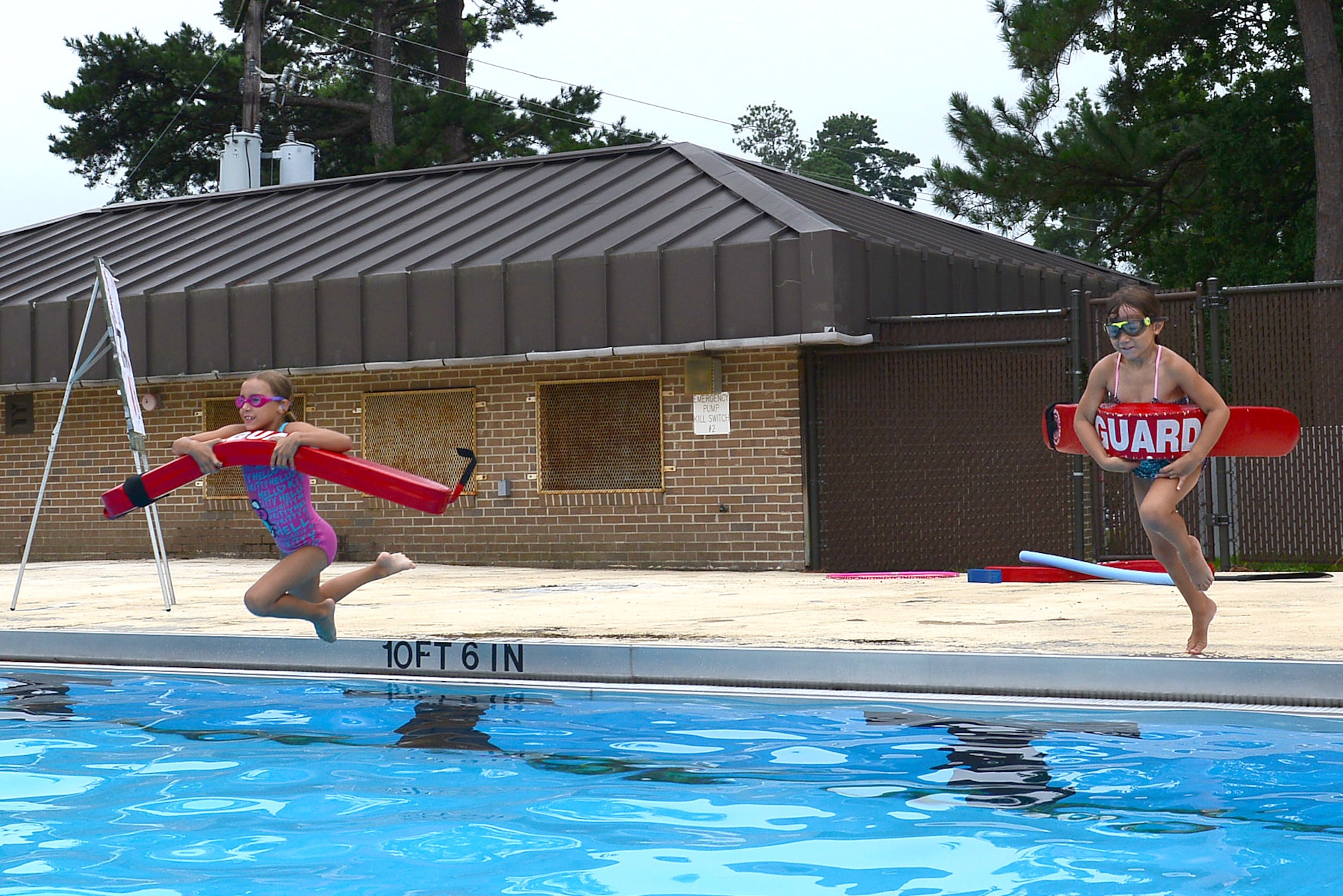 Jaidan and Megan Woods, daughters of Senior Master Sgt. James Woods, 9th Air Force Logistics superintendent, jump into the pool during a rescue scenario at Woodland Pool, Shaw Air Force Base, S.C., Aug. 1, 2014. Along with learning to swim, the children learn what to do if different scenarios occur while in the water to not only assist someone in danger, but keep themselves out of danger. (U.S. Air Force photo by Airman 1st Class Diana M. Cossaboom/Released)
