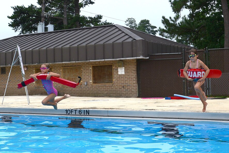 Jaidan and Megan Woods, daughters of Senior Master Sgt. James Woods, 9th Air Force Logistics superintendent, jump into the pool during a rescue scenario at Woodland Pool, Shaw Air Force Base, S.C., Aug. 1, 2014. Along with learning to swim, the children learn what to do if different scenarios occur while in the water to not only assist someone in danger, but keep themselves out of danger. (U.S. Air Force photo by Airman 1st Class Diana M. Cossaboom/Released)