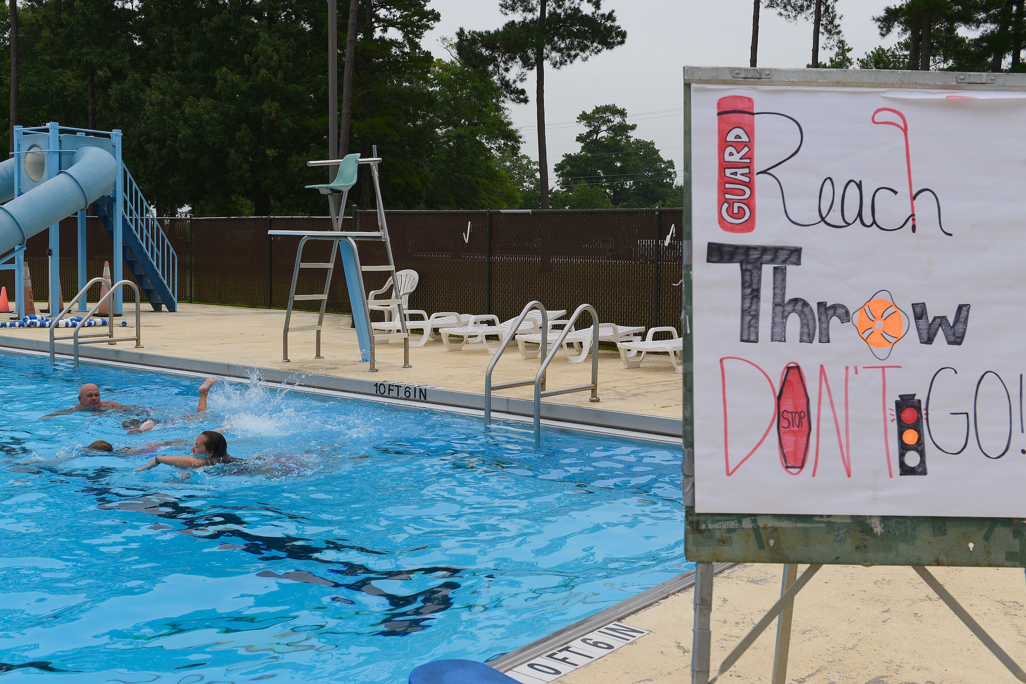 A Woodland Pool lifeguard, Jaidan and Megan Woods, daughters of Senior Master Sgt. James Woods, 9th Air Force Logistics superintendent, and Tim Godwin, 20th Force Support Squadron outdoor recreation director, practice swimming techniques at the Woodland Pool, Shaw Air Force Base, S.C., Aug. 1, 2014. The lesson for today was to teach the children to find something to reach or throw to someone struggling in the water, and not to go into the water to pull them out. (U.S. Air Force photo by Airman 1st Class Diana M. Cossaboom/Released)