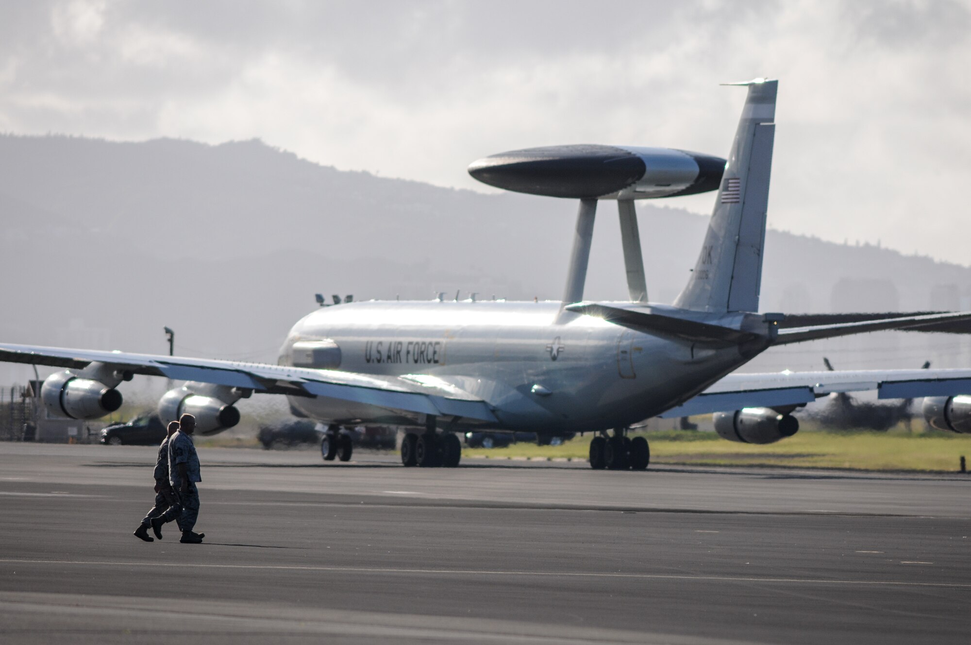Airmen cross the flight line behind an E-3 Sentry Airborne Warning and Control System aircraft flown by Airmen from the 513th Air Control Group at Tinker Air Force Base, Oklahoma, on July 24 at Joint Base Pearl Harbor-Hickam, Hawaii. More than 60 reservists from the 513th Air Control Group traveled from Tinker to participate in the Rim of the Pacific, or RIMPAC, 2014 exercise, the world’s largest maritime exercise held biannually in and around the Hawaiian islands. (U.S. Air Force photo by Staff Sgt. Caleb Wanzer)