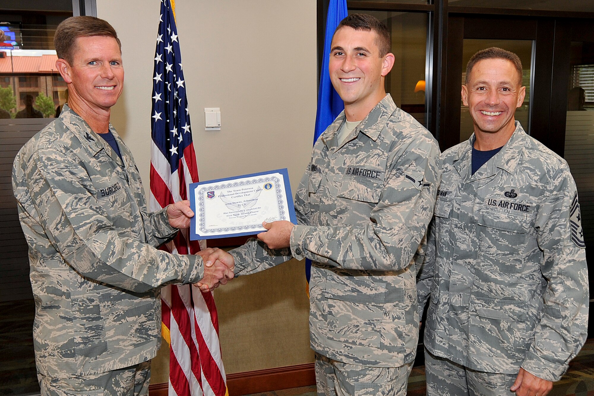 PETERSON AIR FORCE BASE, Colo. — Airman Johnathon Downs (center), poses for a photo while being presented an FTAC certificate of completion July 25 from Col. Richard Burchfield, Individual Mobilization Augmentee to the commander, and Chief Master Sgt. Richard Redman, former 21st SW command chief. (U.S. Air Force photo/Airman 1st Class Rose Gudex)