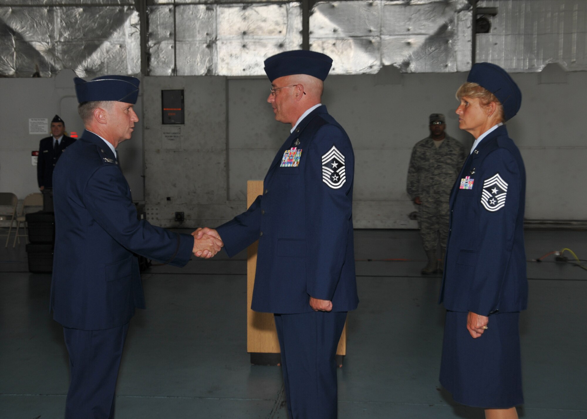 A Command Chief Change of Authority ceremony was held Aug. 2, 2014, in the main hangar at Barnes Air National Guard Base, Westfield, Mass.  Col. James Keefe, 104th Fighter Wing Commander, shook hands with the outgoing Command Chief, Chief Master Sgt. Todd Fappiano, while Command Chief Walts waits to assume authority. (U.S. Air National Guard photo by Master Sgt. Mark Fortin/Released)
