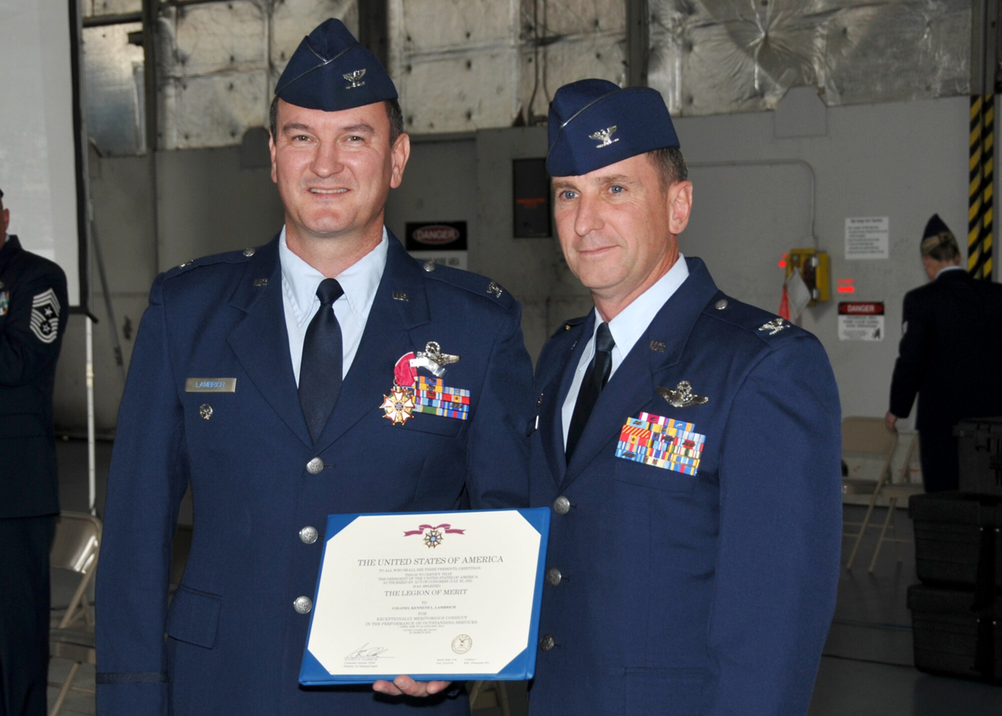 Col. James Keefe, 104th Fighter Wing Commander, presents Col. Kenneth Lambrich with the Legion of Merit in a ceremony held Aug. 2, 2014, in the main hangar at Barnes Air National Guard Base, Westfield, Mass. (U.S. Air National Guard photo by Master Sgt. Mark Fortin/Released)