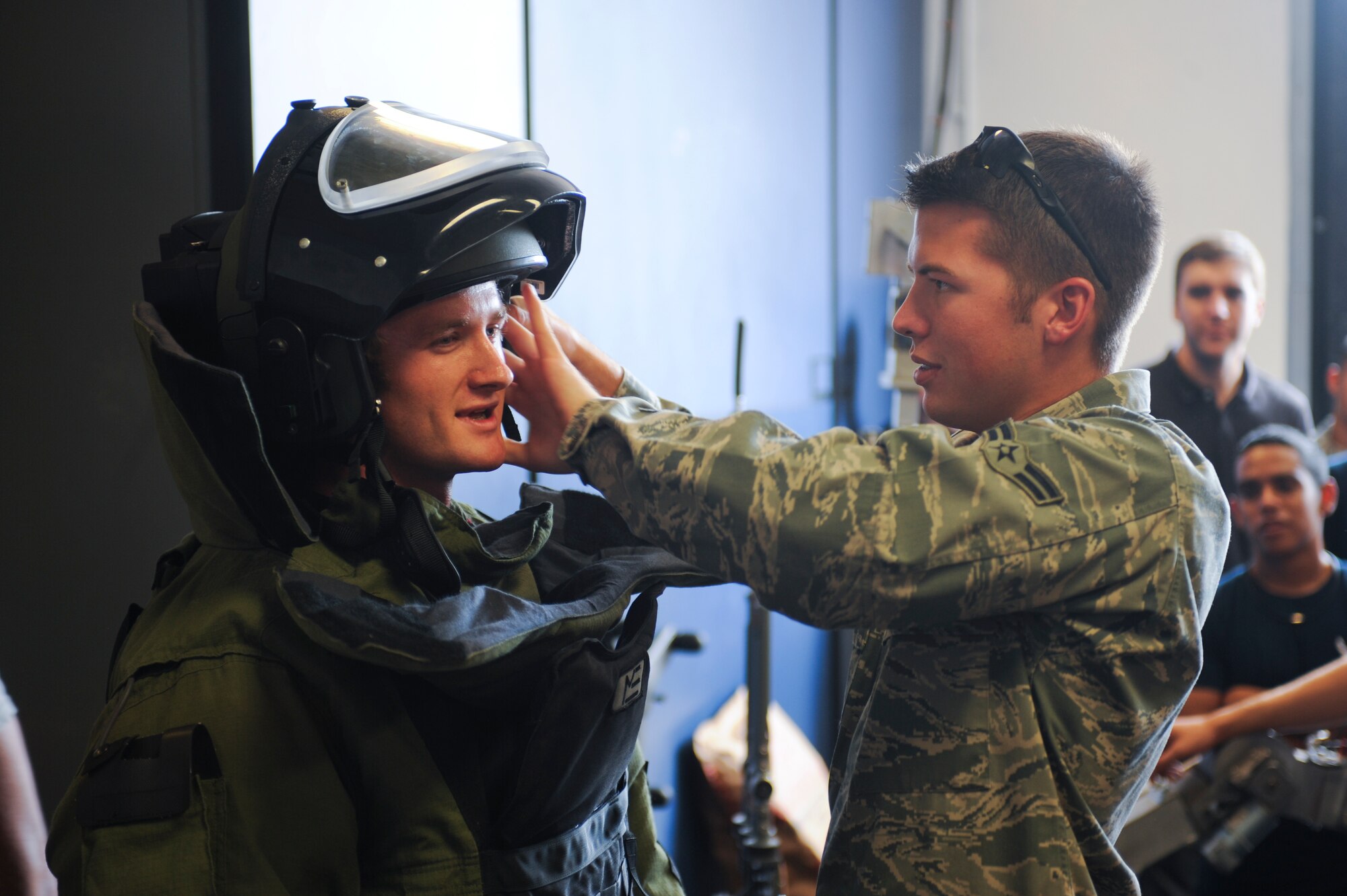 U.S. Air Force Airman 1st Class Jeremy Seybold, 355th Civil Engineer Squadron explosive ordnance disposal technician, helps dawn the bomb suit helmet on Israel Powers, Delayed Enlistment Program member, at Davis-Monthan Air Force Base, Ariz., July 29, 2014. During their visit, the participants received a tour of the facility, basic knowledge of their tools and weapons, and they were able to try on the EOD bomb suit. (U.S. Air Force photo by Airman 1st Class Sivan Veazie/Released)