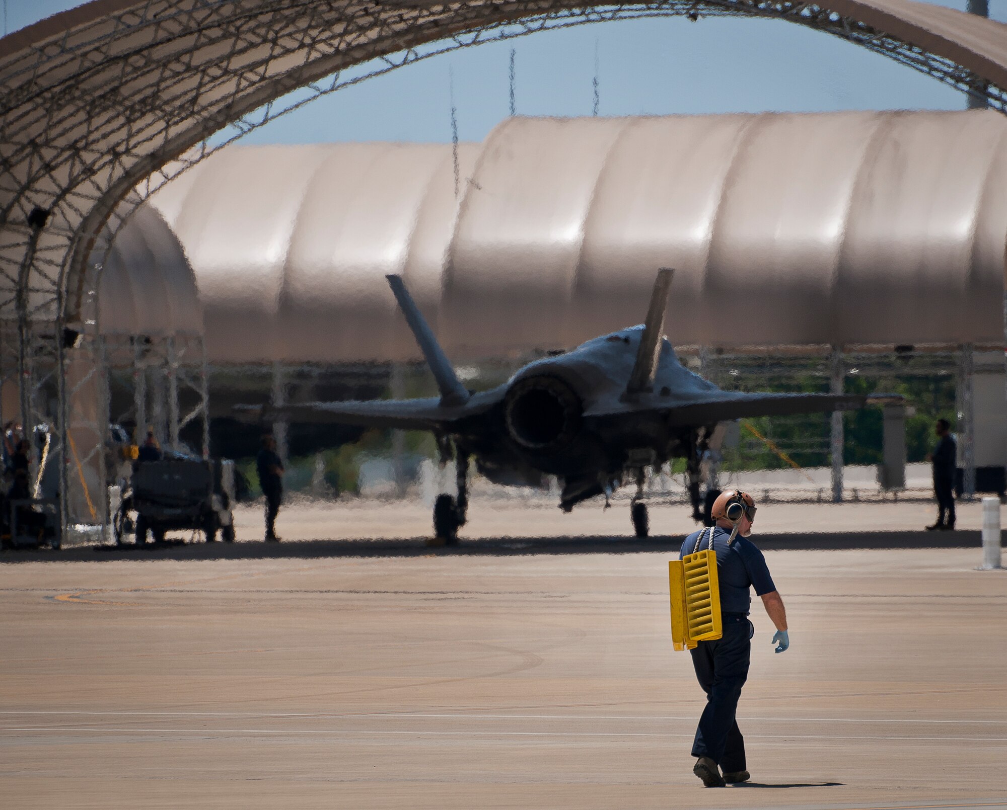 A Lockheed Martin maintainer for the Naval F-35C Lightning II carries wheel chocks back to a hangar after a refueling session at Eglin Air Force Base, Fla.  All of the F-35 variants use the refueling areas in conjunction with the 96th Logistics Readiness Squadron’s fuels flight.  (U.S. Air Force photo/Samuel King Jr.)