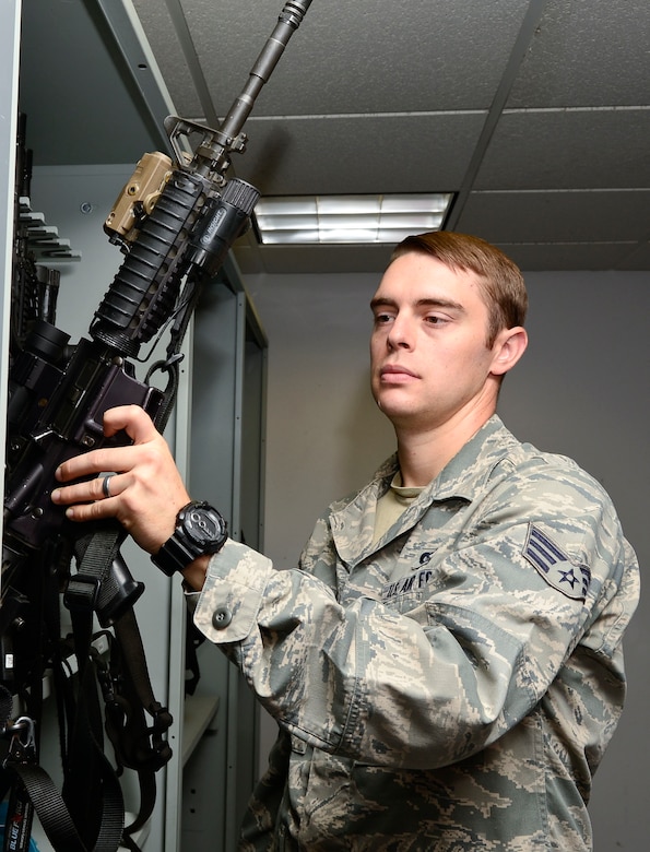 U.S. Air Force Senior Airman James Davis, 633rd Security Forces Squadron armorer, removes a weapon from a rack at Langley Air Force, Va., Aug 1, 2014.  Davis maintains accountability for weapons in the armory and performs a daily inventory to ensure all weapons are secured. The armory is the focal point for all firearms, ammunition and law enforcement equipment for not only the base's security forces personnel, but all assigned Airmen. (U.S. Air Force photo by Senior Airman Connor Estes/Released)
