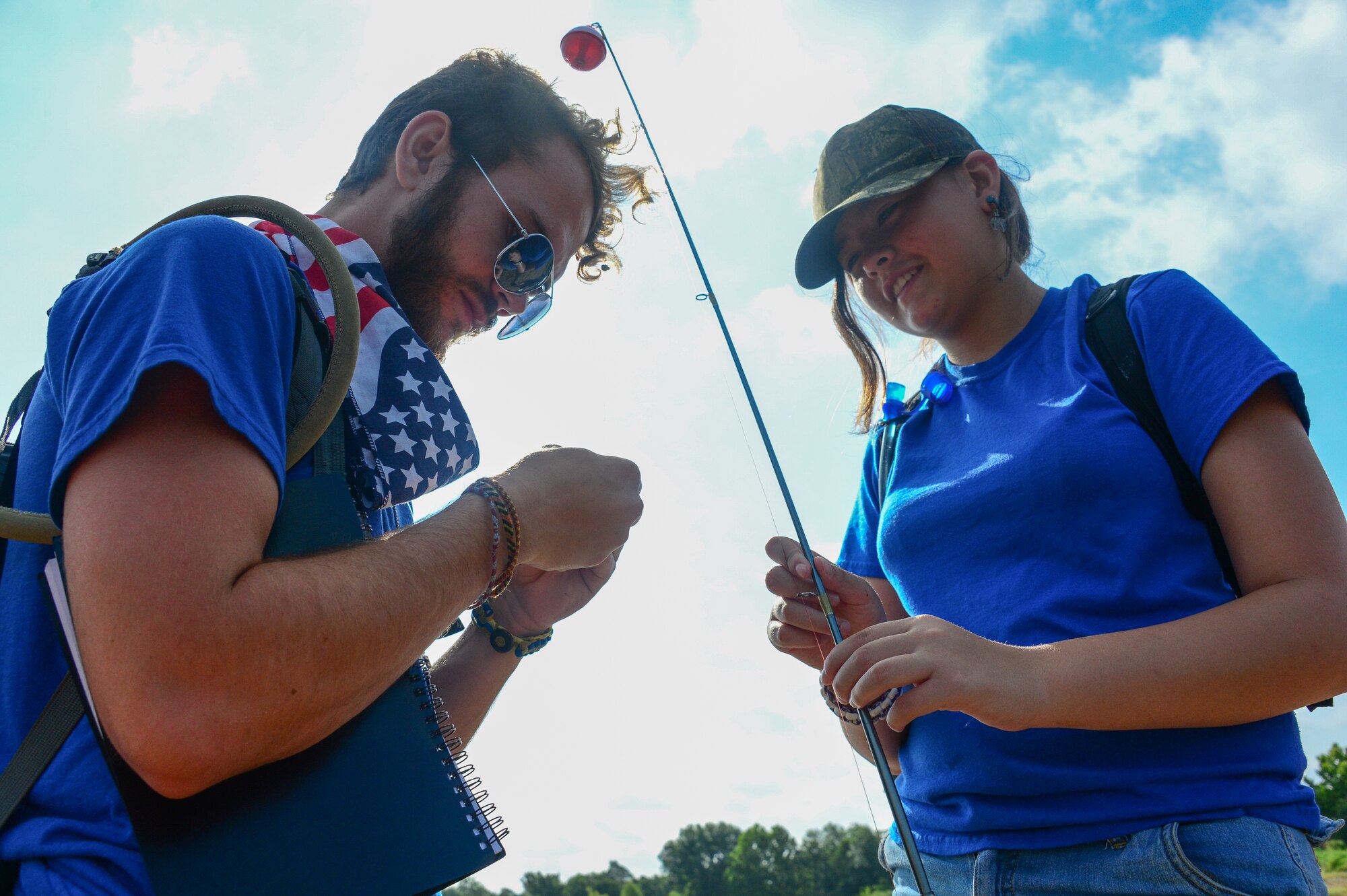 Kids Kamp youth volunteer Brett Keenan assists camper Kailey Hurley while fishing at Camp Gruber, Braggs, Okla., July 25, 2014. The weeklong camp for children of National Guard members focuses on community and teaching core values of both Army and Air Force. (U.S. Air Force photo by Airman 1st Class Tyler Woodward/Released)