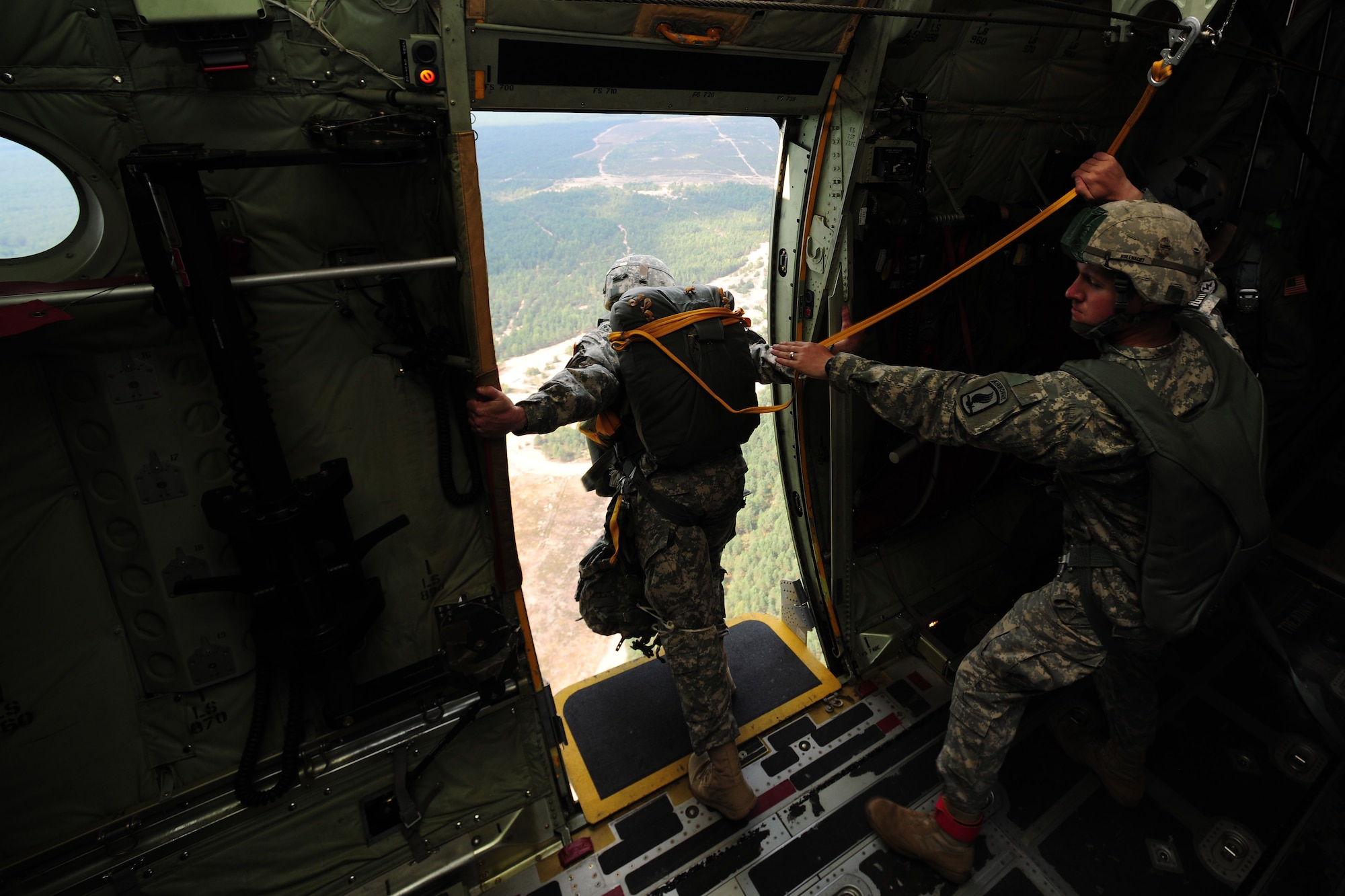 U.S. Army Sgt. David Rufenacht, right, 1-91st Cavalry A-Troop platoon sergeant, holds the harness of Army Staff Sgt. Tyler Trappe, Headquarters and Headquarters Company troop and jumpmaster, as he scans the terrain for a suitable jump location near Siauliai Air Base, Lithuania, July 29, 2014. Army Soldiers and Lithuanian paratroopers were able to hone their jump skills and successfully egress from an in-flight C-130J Super Hercules. (U.S. Air Force photo by Staff Sgt. Jarad A. Denton/Released)
