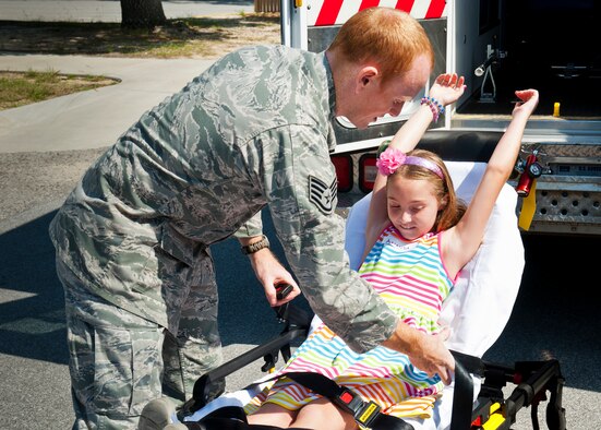 Staff Sgt. Billie Houghton, of the 96th Medical Operations Squadron, secures Amanda Dye in a gurney to demonstrate a medic's duties during the Kid's Career Day at Eglin Hospital July 30. More than 20 children took part in the day-long event to get a hands-on perspective of the various career opportunities available in the medical field as well as the Air Force Medical Service. (U.S. Air Force photo/Sara Vidoni)