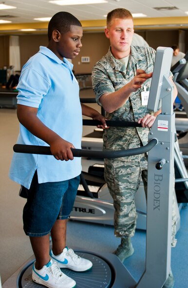 Airman 1st Class Mitchel Rehkamp, of the 96th Medical Operations Squadron, leads Cole Hill in a Biodex Balance Assessment while visiting the Physical Therapy Clinic during the Kid's Career Day at Eglin Hospital July 30. More than 20 children took part in the day-long event to get a hands-on perspective of the various career opportunities available in the medical field as well as the Air Force Medical Service. (U.S. Air Force photo/Sara Vidoni)