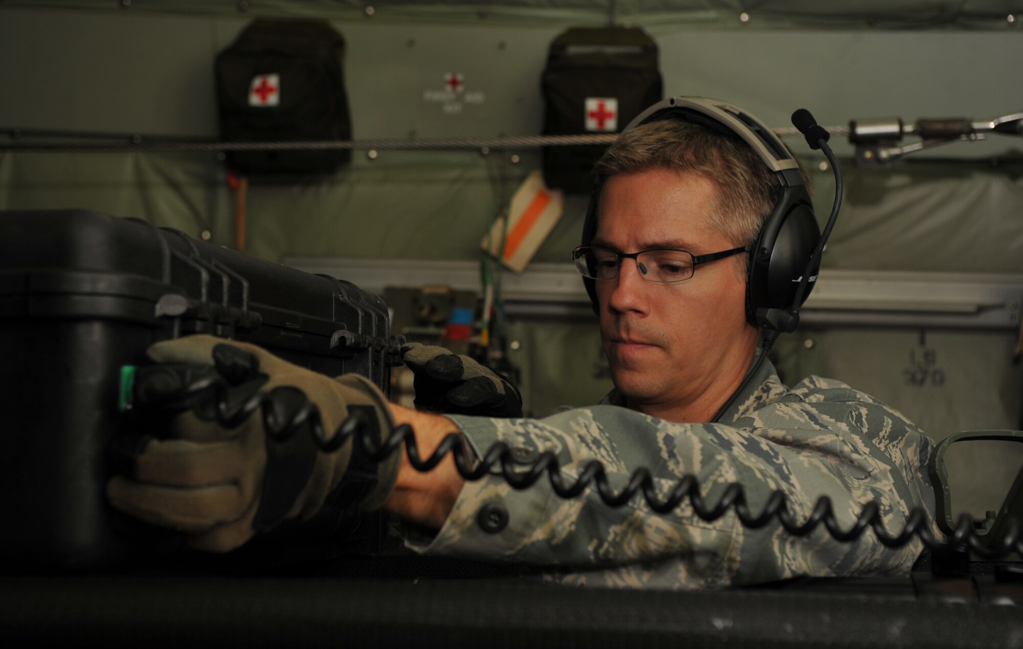 An Airman from the 86th Medical Squadron installs surgical lights onto a liter, converting a C-130J Super Hercules mid-air using a specialized configuration for the first time on a real-world mission, July 26, 2014. There were two surgery tables with patient-monitoring equipment along with several other litters on the C-130. (U.S. Air Force photo/Senior Airman Hailey Haux)