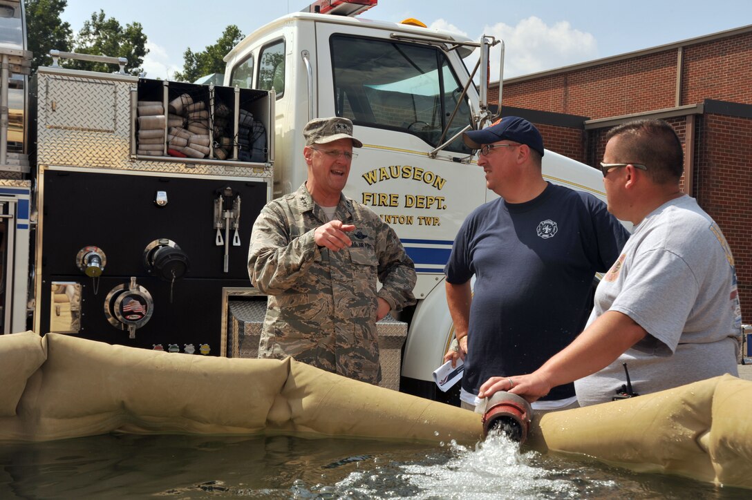 Air Force Maj. Gen. Mark E. Bartman, left, the Ohio Air National Guard's assistant adjutant general, talks with Wauseon Fire Department Capt. Jason Fisher and Phil Kessler, a firefighter, as they fill water bladders with clean water in Holland, Ohio, Aug. 3, 2014. Ohio Gov. John Kasich declared a state of emergency, Aug. 2, 2014, after a harmful algae bloom in Lake Erie contaminated the area's public water system. Fire department members transported water from the area to distribution sites. Ohio Army and Air Guardsmen were activated to help with the water emergency.