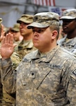 Army Spc. Jonathan Evans, Joint Sustainment Command - Afghanistan, raises his right hand during a re-enlistment ceremony at Kandahar Airfield, Afghanistan, July 4, 2011. Evans is a member of the Mississippi Army National Guard's 184th Expeditionary Sustainment Command.