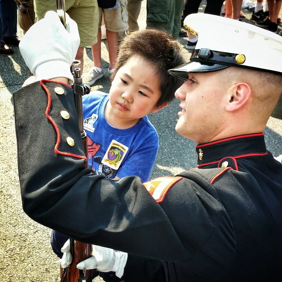 Lance Cpl. Randall Nichols, a member of the U.S. Marine Corps Silent Drill Platoon, shows 5-year-old Seattle native Justin Francisco how to attach a bayonet to Nichols' M1 Garand rifle following a drill performance at the The Museum of Flight during Marine Week Seattle, Aug. 2, 2014. Marine Week, held in Seattle for the first time from July 26 - August 3, is the Marine Corps' largest annual celebration of country, community and Corps. (U.S. Marine Corps photo by Sgt. Reece Lodder)
