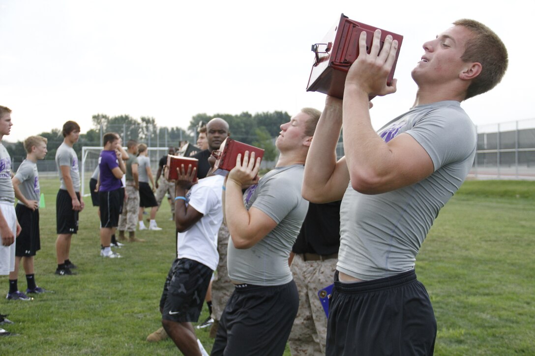 Blue Valley Northwest High School Huskies football players perform ammo-can lifts with 30-pound ammunition cans as Marines from Marine Corps Recruiting Station Kansas City and Recruiting Sub-Station Olathe keep score during the Huskies' Combat Fitness Test as the Huskies' practice field. Aug. 5, 2014. 
