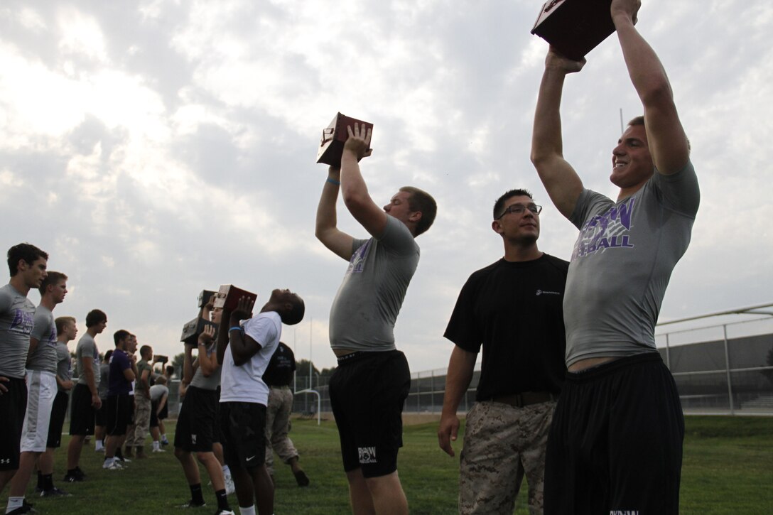 Blue Valley Northwest High School Huskies football players perform ammo-can lifts with 30-pound ammunition cans as Marines from Marine Corps Recruiting Station Kansas City and Recruiting Sub-Station Olathe keep score during the Huskies' Combat Fitness Test as the Huskies' practice field. Aug. 5, 2014. 