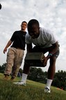 Miles C. Alexander, a senior Blue Valley Northwest Huskies running back and cornerback, bends over and grimaces after performing a number of ammo-can lfts with 30-pound ammunition cans as part of the Combat Fitness Test while Sgt. Michael J. Socin, a Marine Corps Recruiting Station Kansas City, Recruiting Sub-Station Olathe recruitier, looks on at the Huskies' practice field Aug. 5, 2014. The CFT is comprised of an 880-meter run, ammo-can lifts in two minutes, and the maneuver-under-fire.