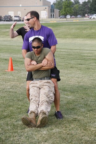 Mike H. Zegunis, the Blue Valley Northwest High School Huskies' head football coach, buddy drags Lance Cpl. Dominic P. Ehretmounivong, a Detachment 2, Supply Company, Combat Logistics Battalion 453 warehouse clerk, to demonstrate the proper way to buddy drag to his players as Staff Sgt. Paul D. Bush, background, the Marine Corps Recruiting Station Kansas City, Recruiting Sub-Station Olathe staff noncomissioned officer-in-charge, advises on proper technique at the Huskies' practice field Aug. 5, 2014. 