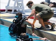 A Navy Diver aids a Special Amphibious Reconnaissance Corpsman exit a pool during proficiency dive training aboard Camp Pendleton, Calif., July 22. The SARCs were supported by Navy Divers from 1st Reconstruction consolidated dive locker.