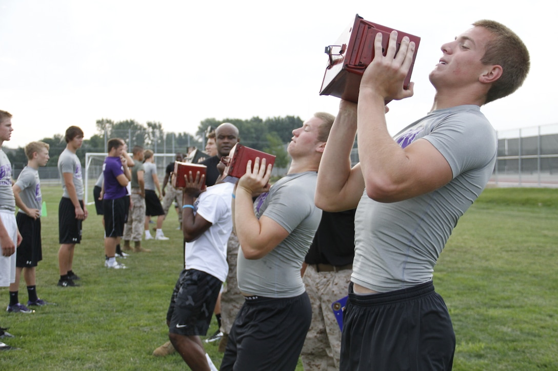Blue Valley Northwest High School Huskies football players perform ammo-can lifts with 30-pound ammunition cans as Marines from Marine Corps Recruiting Station Kansas City and Recruiting Sub-Station Olathe keep score Aug. 5, 2014 during the Huskies' Combat Fitness Test as the Huskies' practice field. 