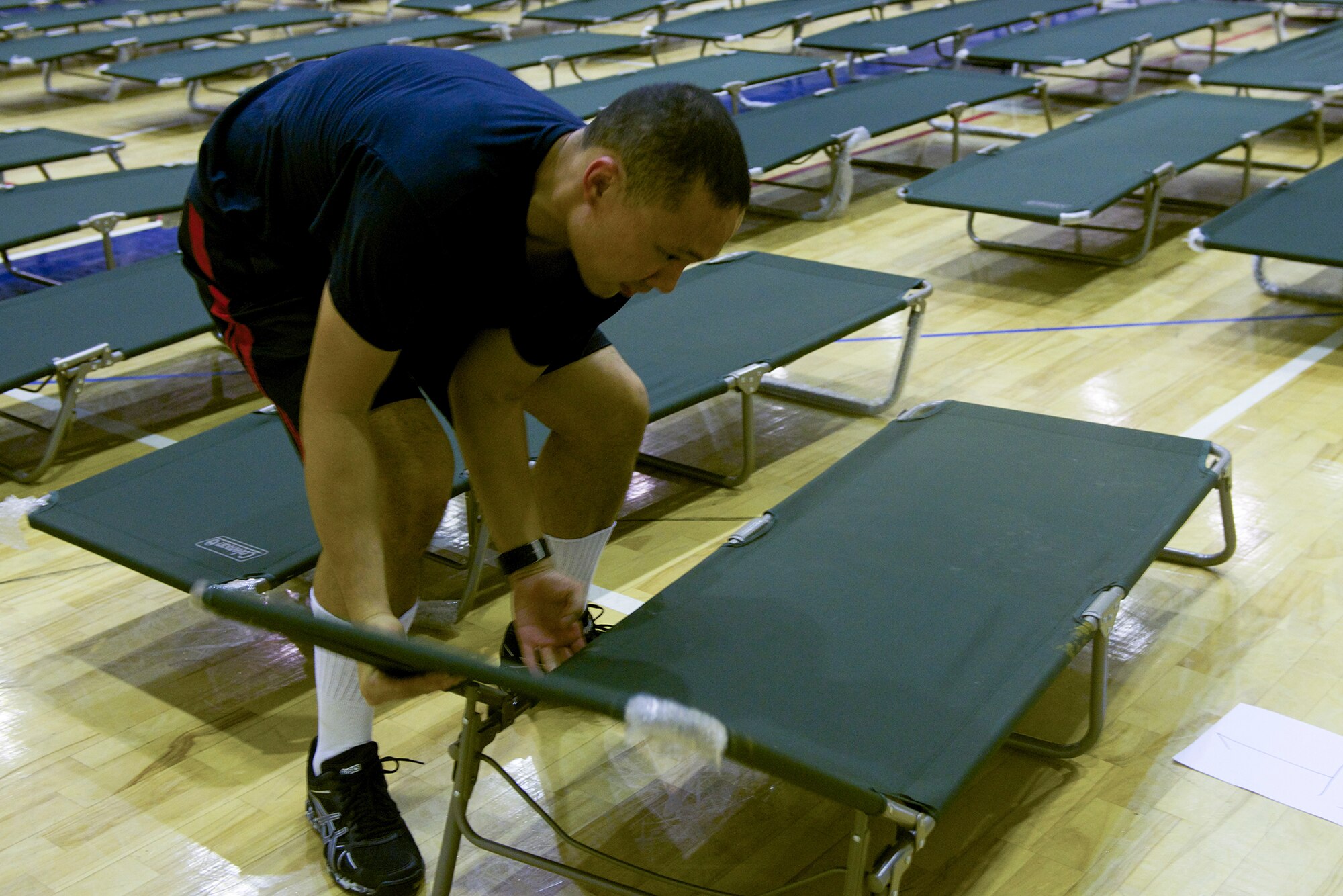 Staff Sgt. James Callaway, 374th Force Support Squadron food services supervisor, sets up cots at Yokota Air Base, Japan, Aug. 1, 2014. Volunteers at Yokota helped prepare accommodations for passengers whose rotator flights were delayed due to a monsoonal trough passing through Okinawa, Japan. (U.S. Air Force photo by Airman 1st Class David C. Danford/Released)