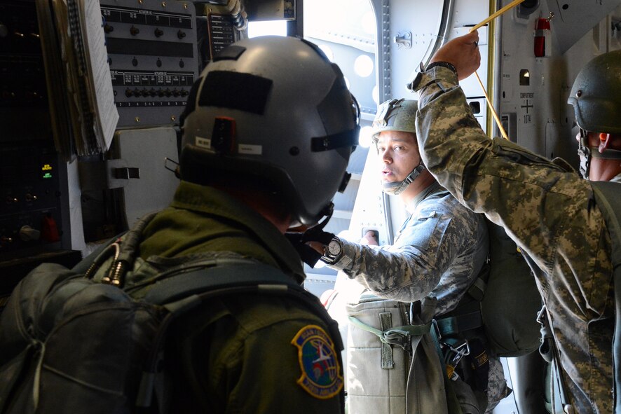 Army Master Sgt. Miguel Taveras (left), 1st Special Forces Group (Airborne) 112th Chemical Recon Detachment sergeant and jump master, looks at Senior Master Sgt. RJ Bertsch, 728th Airlift Squadron loadmaster, for jump instructions during joint Operation Desert Cougar Aug. 4, 2014, near Schoonover, Calif. As a jump master, Taveras supervised the jumper’s exiting the aircraft before performing his own jump. (U.S. Air Force photo/Airman 1st Class Jacob Jimenez) 