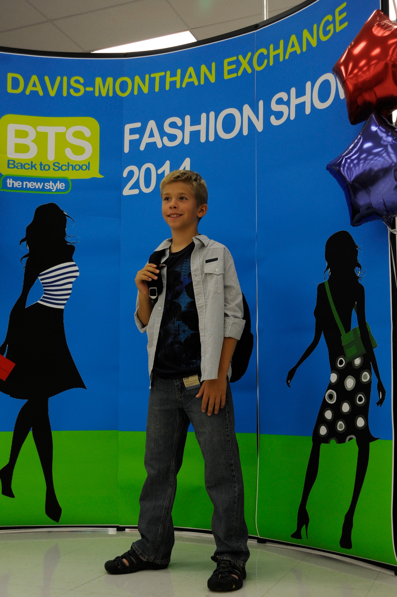 Cody Thiel, son of Lt. Col. Jeremy Thiel, 612th Support Squadron, poses for a crowd during a fashion show at Davis-Monthan Air Force Base, Ariz., Aug. 2, 2014. The Back-to-School Fashion Show was held by the BX and Enlisted Spouse Association to showcase what clothing the BX has to offer this fall. (U.S. Air Force photo by Airman 1st Class Betty R. Chevalier/Released)