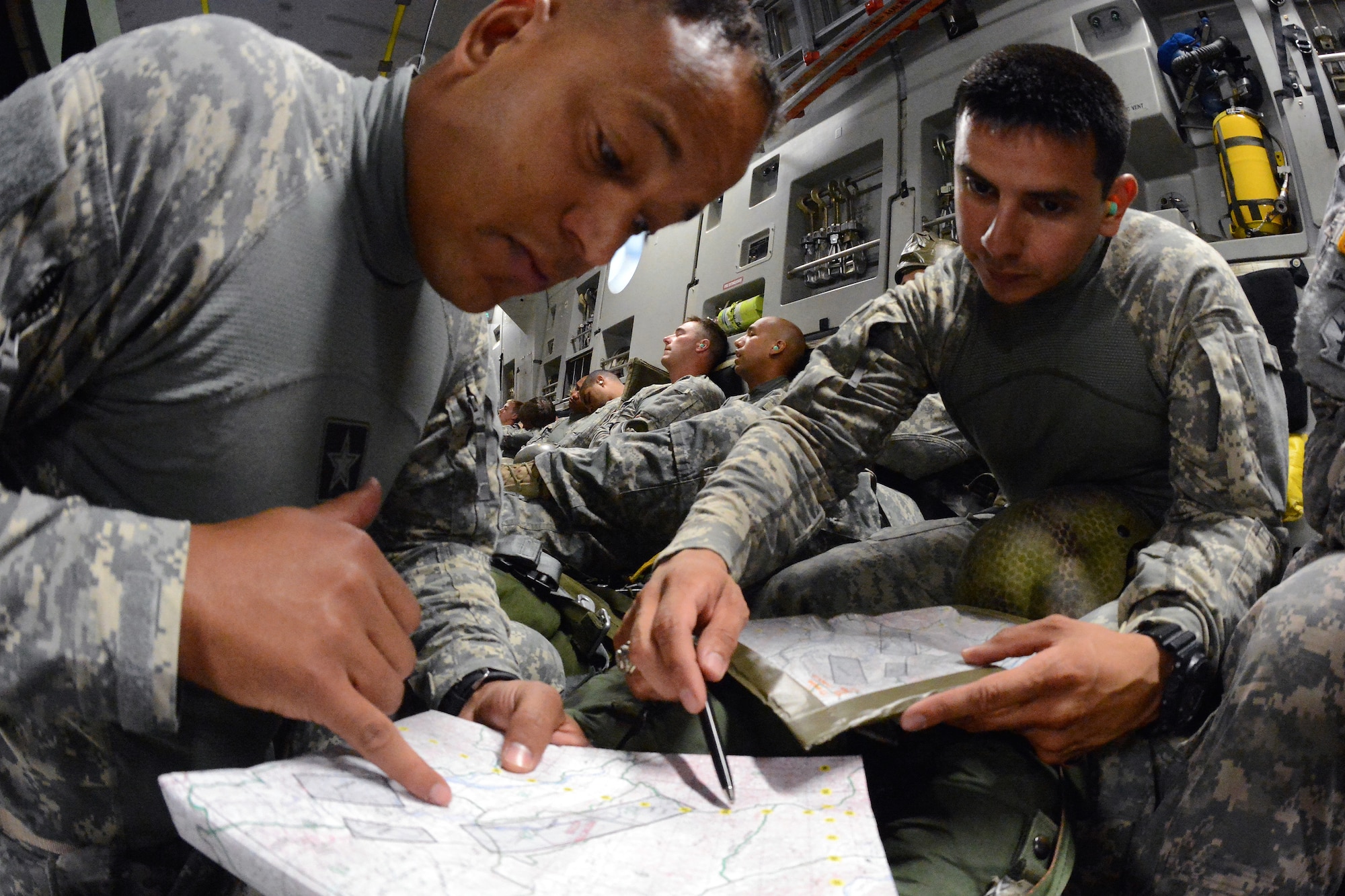 Army Master Sgt. Miguel Taveras (left), 1st Special Forces Group (Airborne) 112th Chemical Recon Detachment sergeant and jump master, and Capt. Army Alberto Rios, 1st SFG (A), 112th CRD commander, review the jump insertion zone on a map Aug. 4, 2014, while enroute to Schoonover, Calif. Taveras was one of four jump masters to participate in the joint Operation Desert Cougar exercise to ensure safe static-line jumps. (U.S. Air Force photo/Airman 1st Class Jacob Jimenez)
