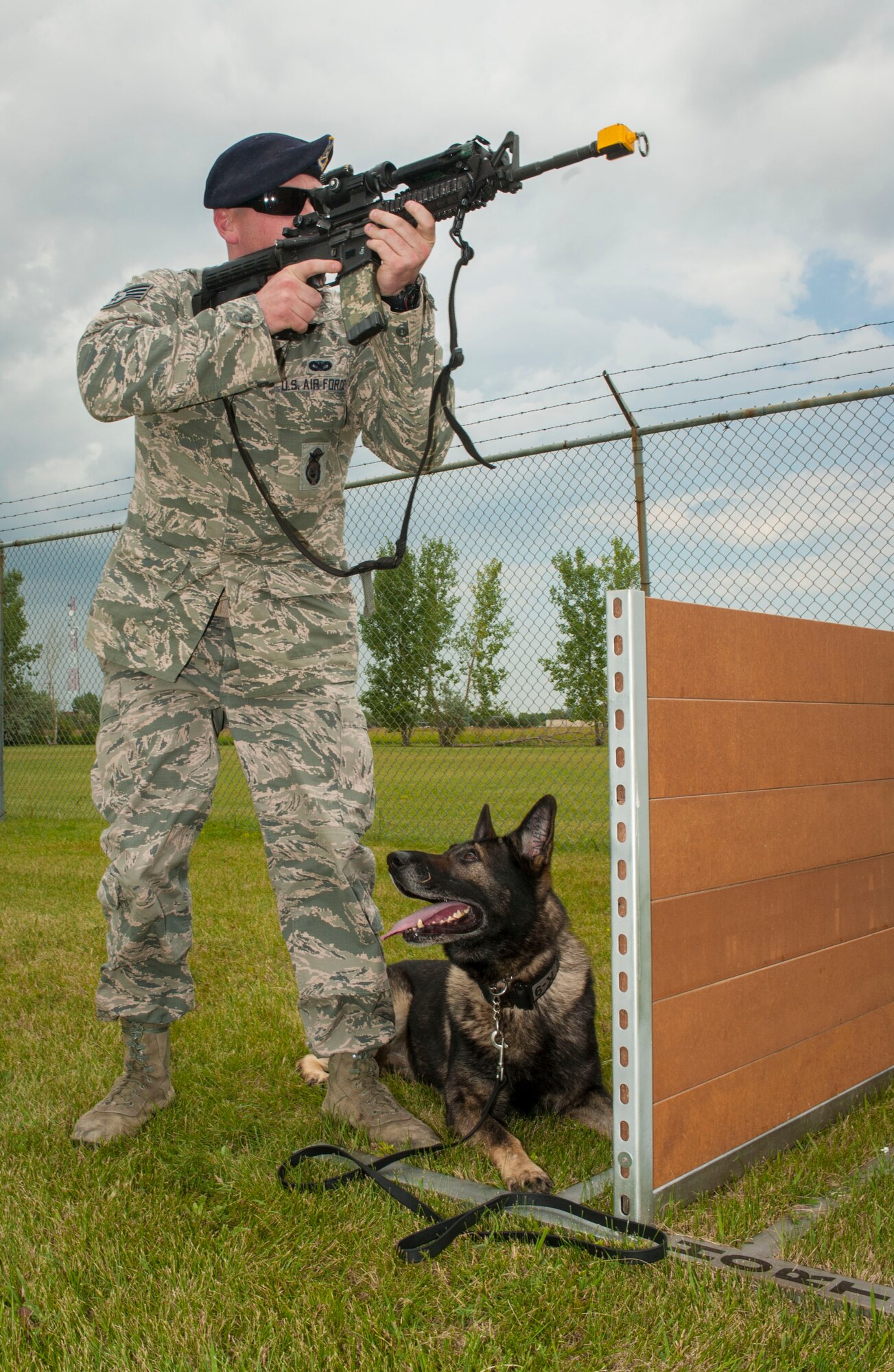 Staff Sgt. Tim Glover, 5th Security Forces Squadron military working dog handler, completes weapons training with his MWD Roko on Minot Air Force Base, N.D., July 28, 2014. During training, Glover used blank rounds to test Roko’s reaction to the sound of gunfire and his ability to obey commands in a stressful environment. (U.S. Air Force photo/Senior Airman Stephanie Morris)