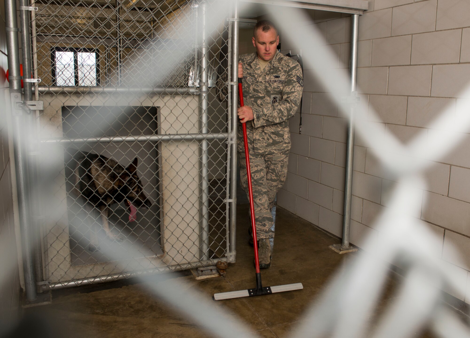 Staff Sgt. Tim Glover, 5th Security Forces Squadron military working dog handler, cleans the kennel of his MWD Roko on Minot Air Force Base, N.D., July 28, 2014. After watching MWD handlers work at his last base, Glover decided  he wanted to specialize and applied to become one. (U.S. Air Force photo/Senior Airman Stephanie Morris)