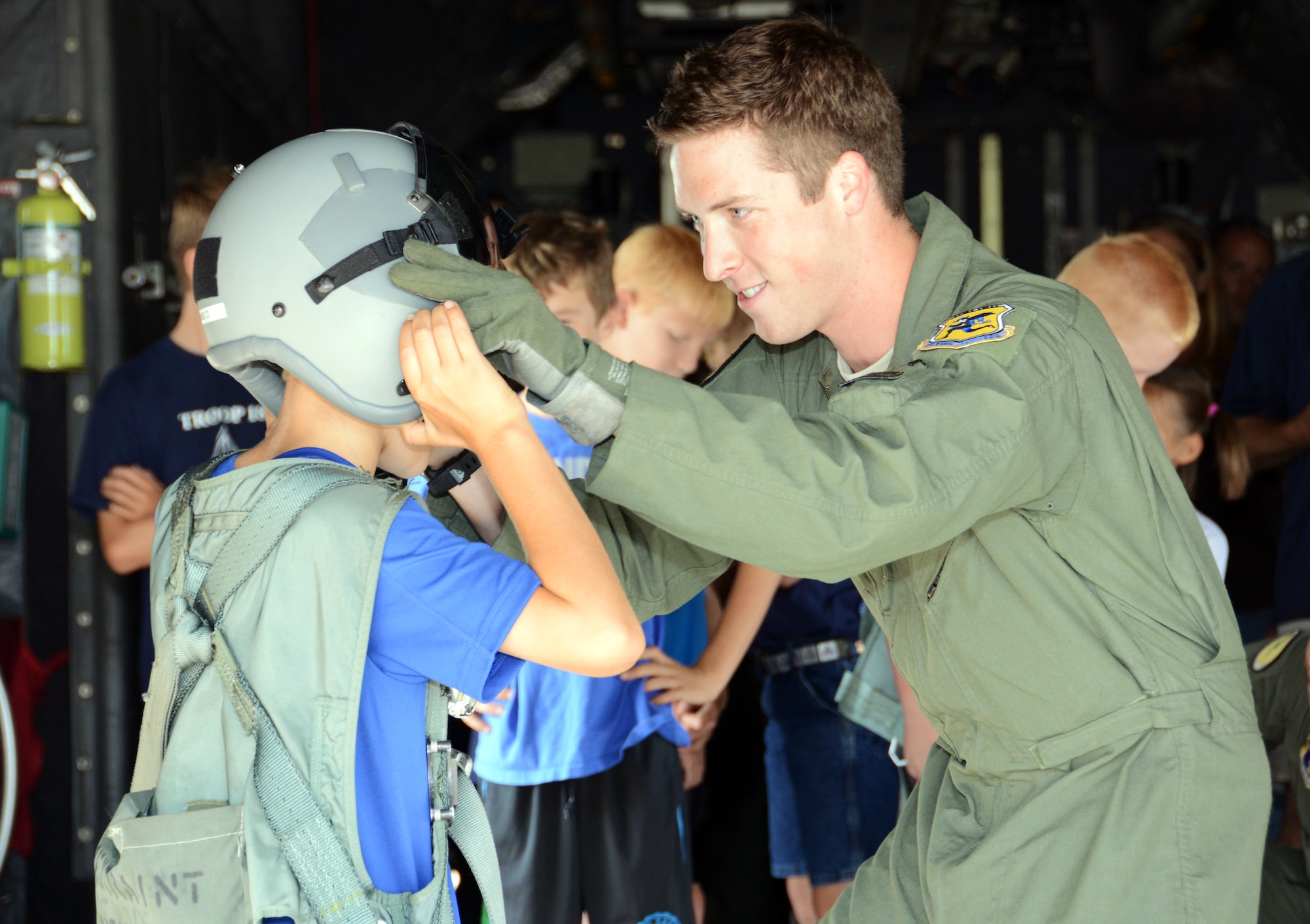 Staff Sgt. Daniel Haynes, a loadmaster with the 118th Airlift Squadron, adjusts an aviation helmet on Cub Scout Blake Kamoen, 8, during a base tour at Bradley Air National Guard Base in East Granby, Conn., Aug. 4, 2014. Haynes later said that tours like these are part of the reason he joined the Air Force. (U.S. Air National Guard photo by Tech. Sgt. Joshua Mead/Released)