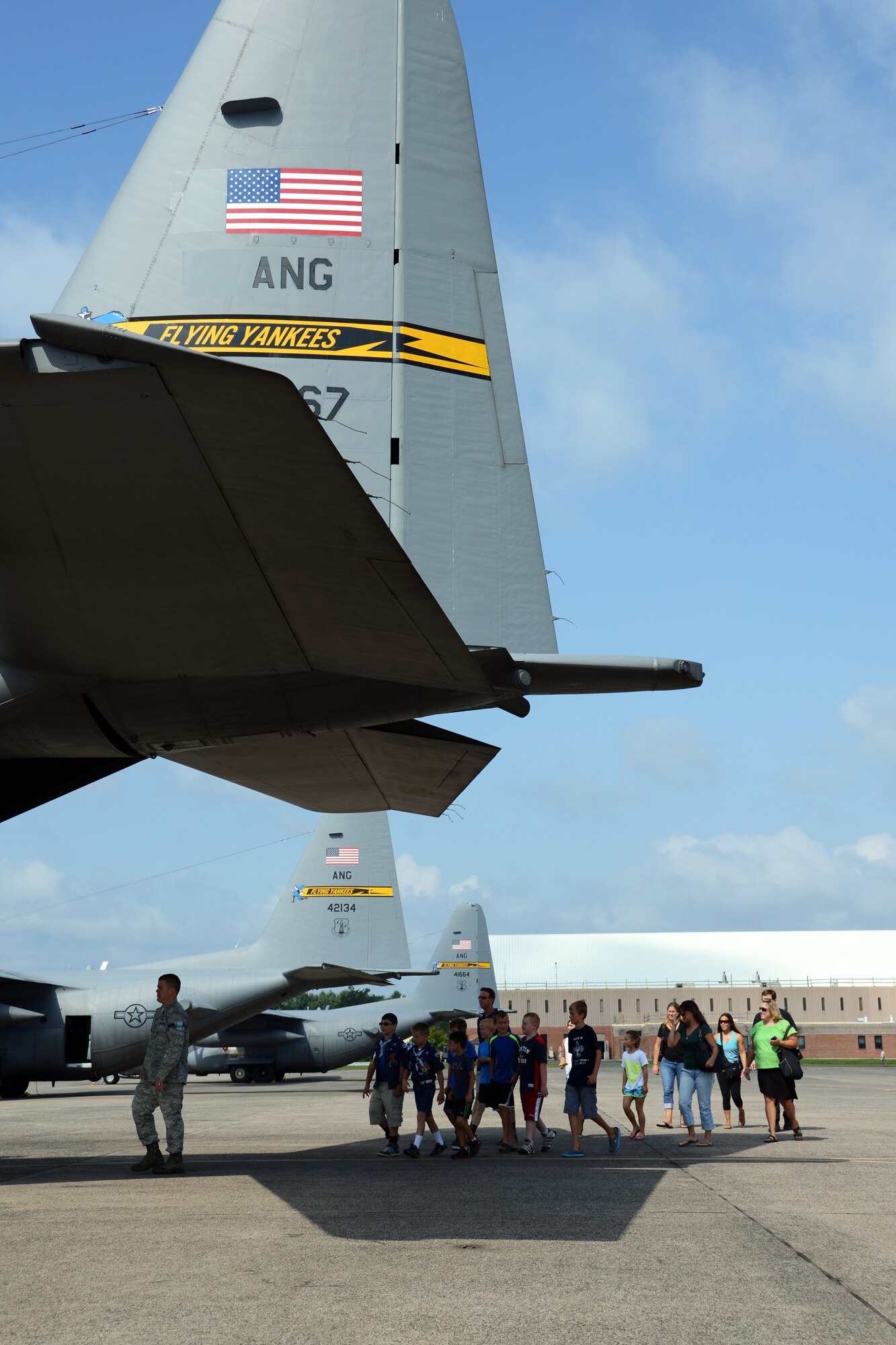 Maj. Bryon Turner, public affairs officer with the 103rd Airlift Wing, leads a group of Cub Scouts out to a C-130H Hercules aircraft on the flightline at Bradley Air National Guard Base, East Granby, Conn., Aug. 4, 2014. The Cub Scouts were able to climb into the cockpit of the aircraft and don some equipment used by the loadmasters. (U.S. Air National Guard photo by Tech. Sgt. Joshua Mead/Released)