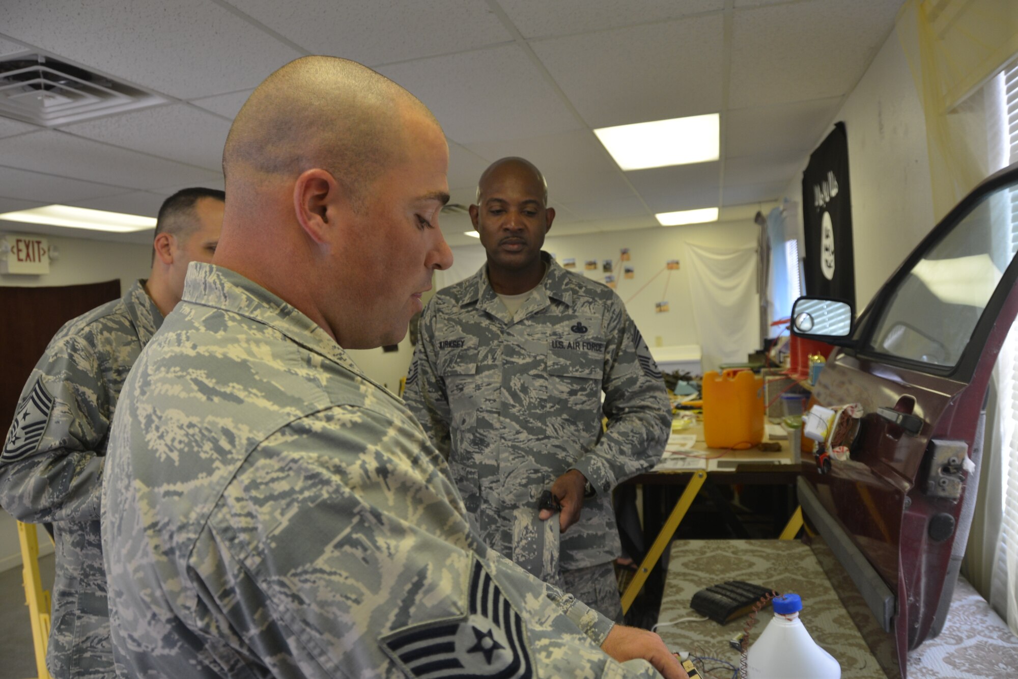 Tech. Sgt. Adam Alderman (forefront), military training instructor, 319th Training Squadron, Joint Base San Antonio-Lackland, Texas, at one of the zones at the “BEAST” (Basic Expeditionary Airman Skills Training), Aug. 1, 2014 explains the display of a make-shift IED to Command Chief Master Sgt. Cameron Kirksey, Air Force Reserve Command, Robins Air Force Base, Georgia that are on display for trainee familiarization.  (U.S. Air Force photo by Minnie Jones)