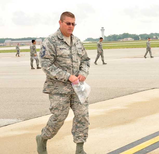 Senior Master Sgt. Todd Wadkins, 932nd Ground and weapons safety NCO, walks the flight line with members of the 932nd Airlift Wing, and the 375th Air Mobility Wing, picking up objects that can be considered foreign object damage, such as small rocks and debris, during a weekly FOD walk on Scott Air Force Base, Aug 5, 2014. The FOD walk is done to help prevent mishaps with aircraft, and protect assets and mission capabilities. (U.S. Air Force photo / Staff Sgt. Amber Hodges)