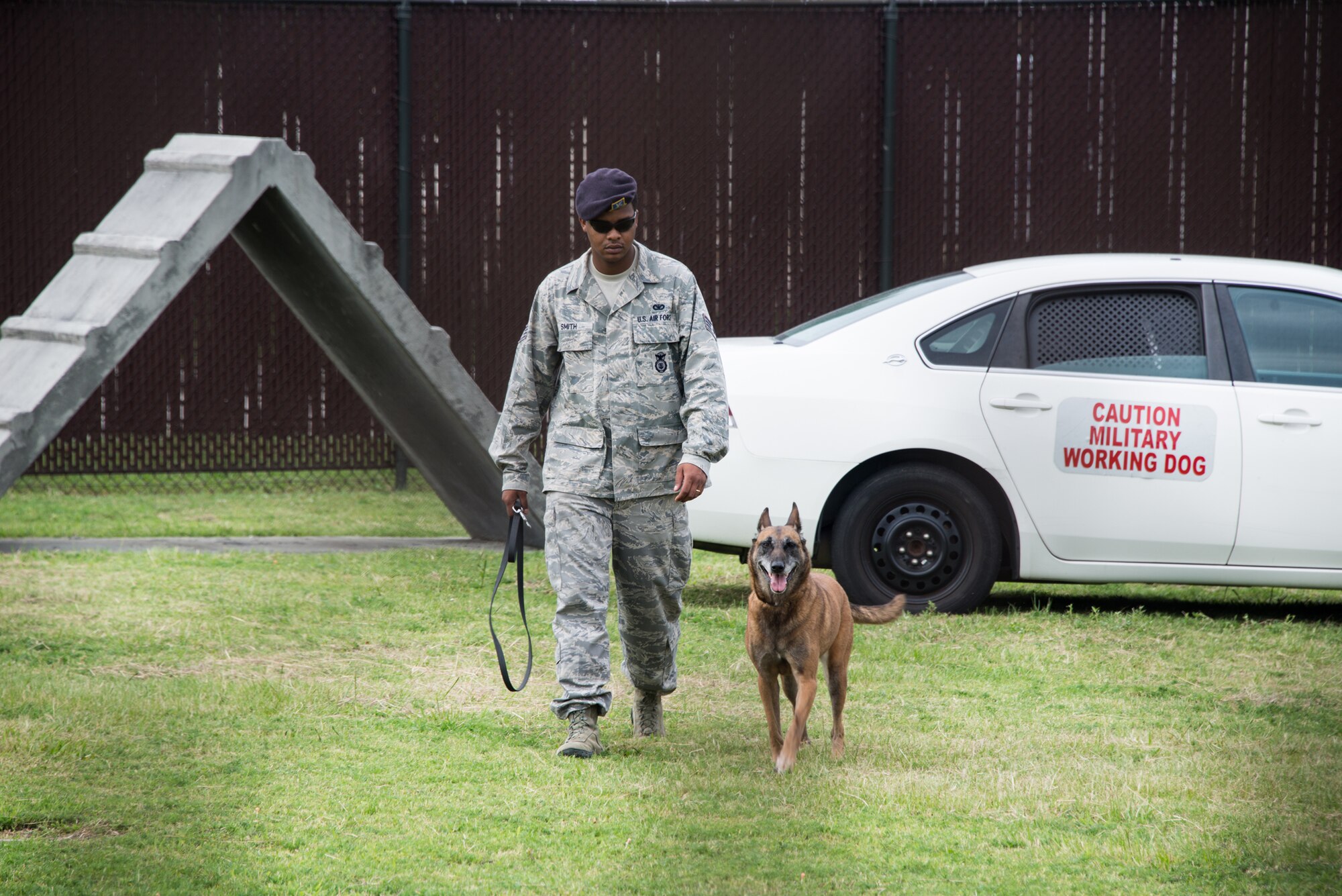 Staff Sgt. Kyle Smith, 81st Security Forces Squadron, and Densy, a military working dog, walk through the obstacle course used for training military working dogs Aug. 1, 2014, at the K-9 facility, Keesler Air Force Base, Miss. Children from the child development center and the youth center participated in the tour.  (U.S. Air Force photo by Marie Floyd)