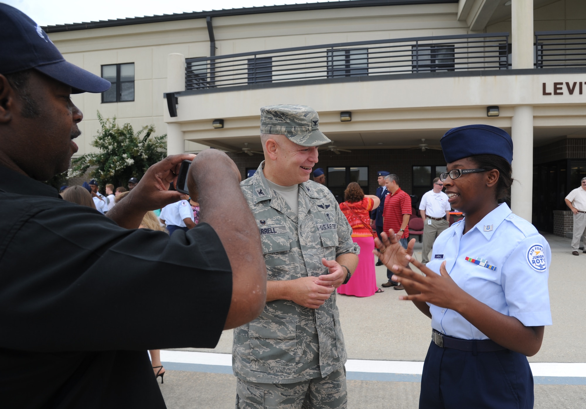 Col. Thomas Harrell, 81st Medical Group commander, speaks with Cadet Rosemarie Marshall, a sophomore from Biloxi High School, as her pastor from Prince of Peace Baptist Church, Darrell Taylor, takes a photo of them following a parade Aug. 1, 2014, at the Levitow Training Support Facility, Keesler Air Force Base, Miss.  Approximately 100 JROTC students from seven states attended a week-long JROTC Summer Leadership School at Keesler that ended with the parade and a graduation ceremony at the Welch Theater. (U.S. Air Force photo by Kemberly Groue)