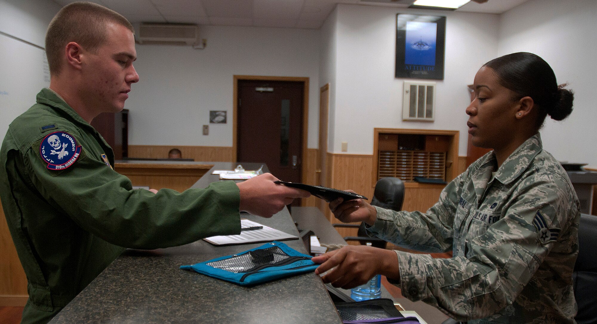 Senior Airman Dorothy Hannibal, 90th Logistics Readiness Squadron vehicle operations, hands a set of keys for a government operated vehicle to a missileer July 31, 2014, at the vehicle operations. Vehicle operations issue out GOVs for missileers on alert traveling to their missile alert facility. (U.S. Air Force photo by Airman Malcolm Mayfield)