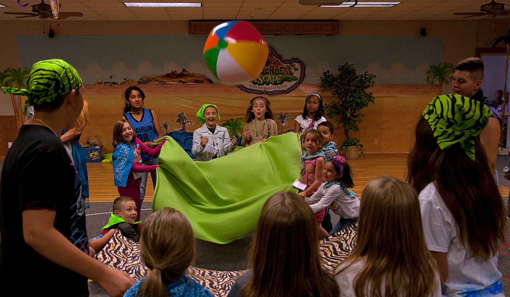 140730-F-GZ967-057 Children pass a beach-ball back and forth between two different groups July 30, 2014, during a Vacation Bible School in the Chapel Activities Center, F.E. Warren Air Force Base, Wyo. The activity required the groups to work as a team and to coordinate with one another to pass the ball with just the pull of a sheet. (U.S. Air Force photo by Airman 1st Class Brandon Valle)