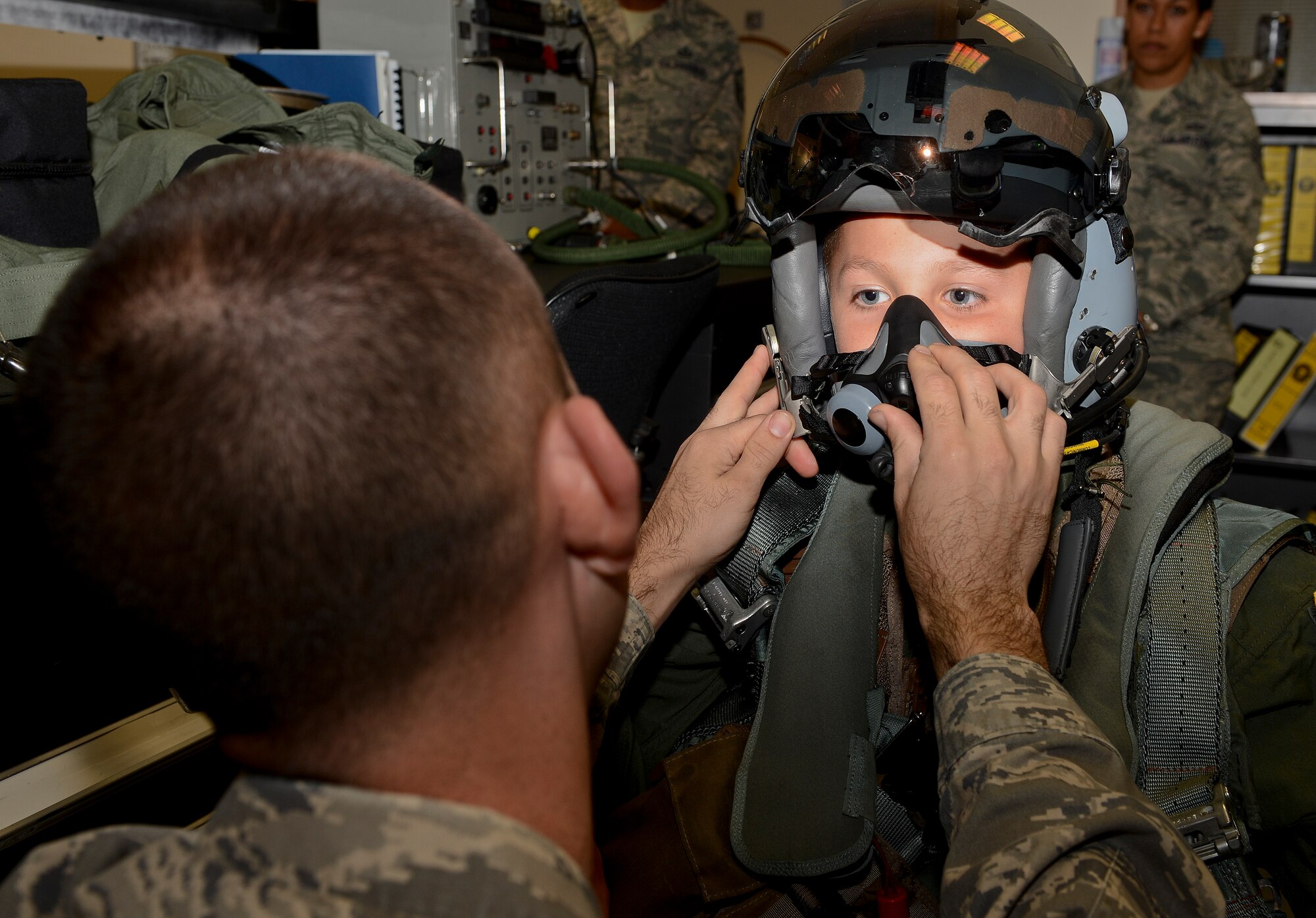 Senior Airman Jeffrey Berry, 493rd Fight Squadron aircrew flight equipment journeyman, fits a fighter jet helmet on Sam Jerred, 9, during a “Pilot for a Day” event at Royal Air Force Lakenheath, England, Aug. 4, 2014. The program gives the opportunity for local children with serious illnesses and conditions to learn about the Air Force mission, and it provides them with a day to escape their normal hospital routine. (U.S. Air Force photo by Airman 1st Class Trevor T. McBride/Released)