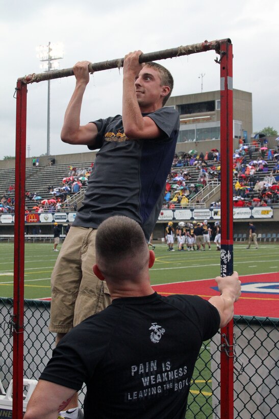 U.S. Marine Corps Staff Sgt.  Joshua Young, recruiter at Permanent Contact Station Ohio Valley, Recruiting Sub-Station Zanesville, steadily holds the pull-up bar for a participant of the pull-up challenge during the 69th Annual Rudy Mumley Ohio Valley Athletic Conference All-Star football game in Wheeling, Ohio, July 27, 2014. The pull-up challenge gave fans from the Ohio and West Virginia a means to compete against each other for the most total pull-ups. (U.S. Marine Corps photo by Sgt. T.M. Stewman/Released)