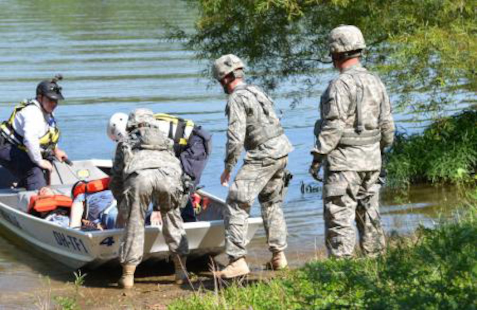 Brian Harting, a rescue team member from Task Force 1, Ohio's Federal Emergency Management Team, prepares to deliver a simulated casualty to a litter team of Soldiers from the 381st Military Police Company, Indiana National Guard, Brush Creek Reservoir in Butlerville, Ind., near Muscatatuck Urban Training Center, Aug. 4, 2014. The Vibrant Response 14 exercise tests the abilities of multiple agencies to respond in the event of an actual chemical, biological, radioactive or nuclear incident or other emergencies. 