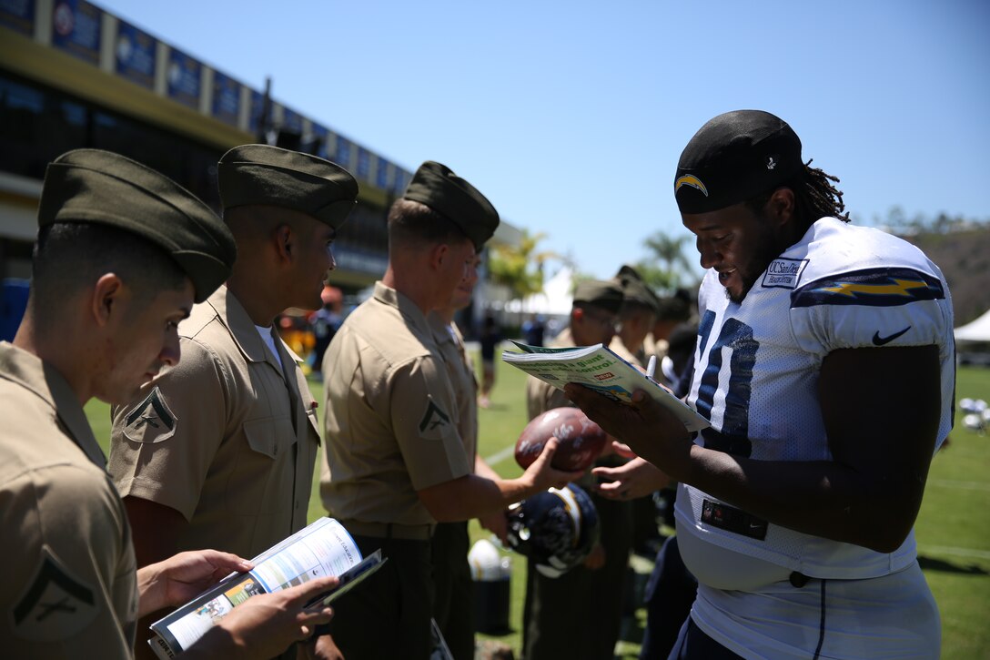 D.J. Johnson, guard for the San Diego Chargers, signs memorabilia for Marines and Sailors at the San Diego Chargers' Training Facility, Aug. 5.  The San Diego Chargers and USAA hosted Marines and Sailors of 3rd Marine Aircraft Wing and Marine Corps Air Station Miramar at their training camp to give Service members a chance to witness practice firsthand and intereact with players and coaches throughout the event.