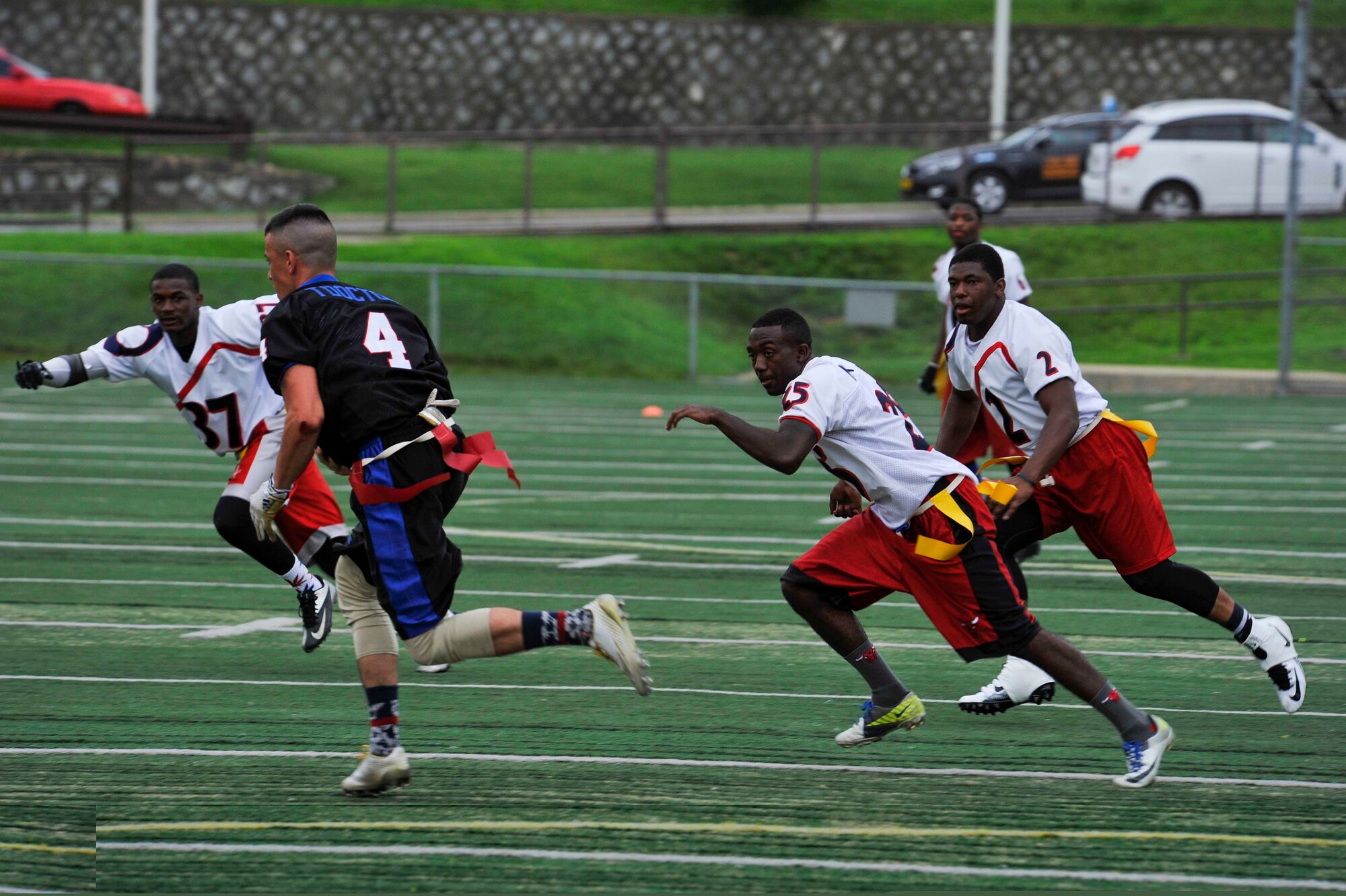 Members of the Osan flag football team chase after the quarterback for Camp Carroll Army Base, Republic of Korea, in the second half of the game the high school football field on Osan Air Base, ROK, Aug. 2, 2014. Osan’s Team 1 defeated Camp Carroll to move to the semifinals. (U.S. Air Force photo/Senior Airman David Owsianka)